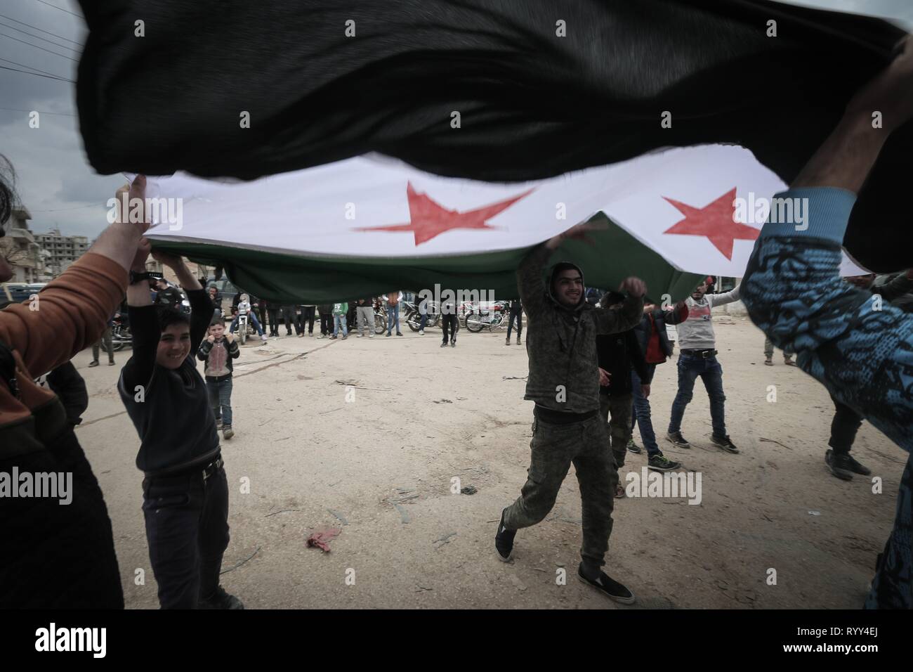 Siri sono visti trattenere un flag di opposizione durante la celebrazione. Siri nella città di Bensh, che si trova a est di Idlib e controllati dall'opposizione, celebrato l'ottavo anniversario della rivolta contro il regime del Presidente Bashar al-Assad. Foto Stock