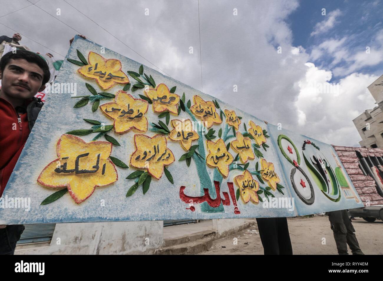 Siri sono visti tenendo un banner durante la celebrazione. Siri nella città di Bensh, che si trova a est di Idlib e controllati dall'opposizione, celebrato l'ottavo anniversario della rivolta contro il regime del Presidente Bashar al-Assad. Foto Stock