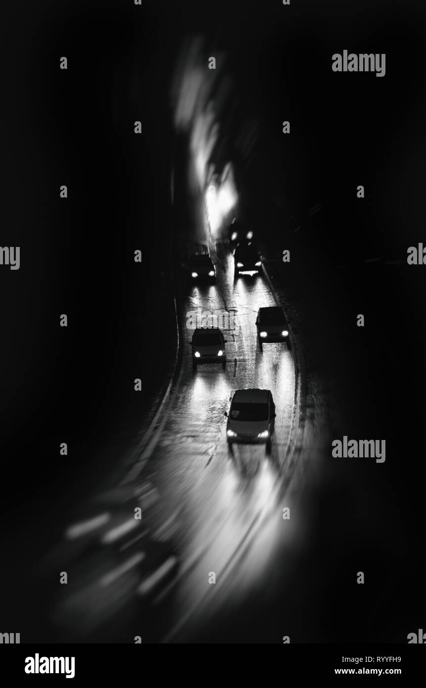 Auto guidare sotto la pioggia durante la notte, motion blur, in bianco e nero arte sfondo, per la copertina del libro Foto Stock