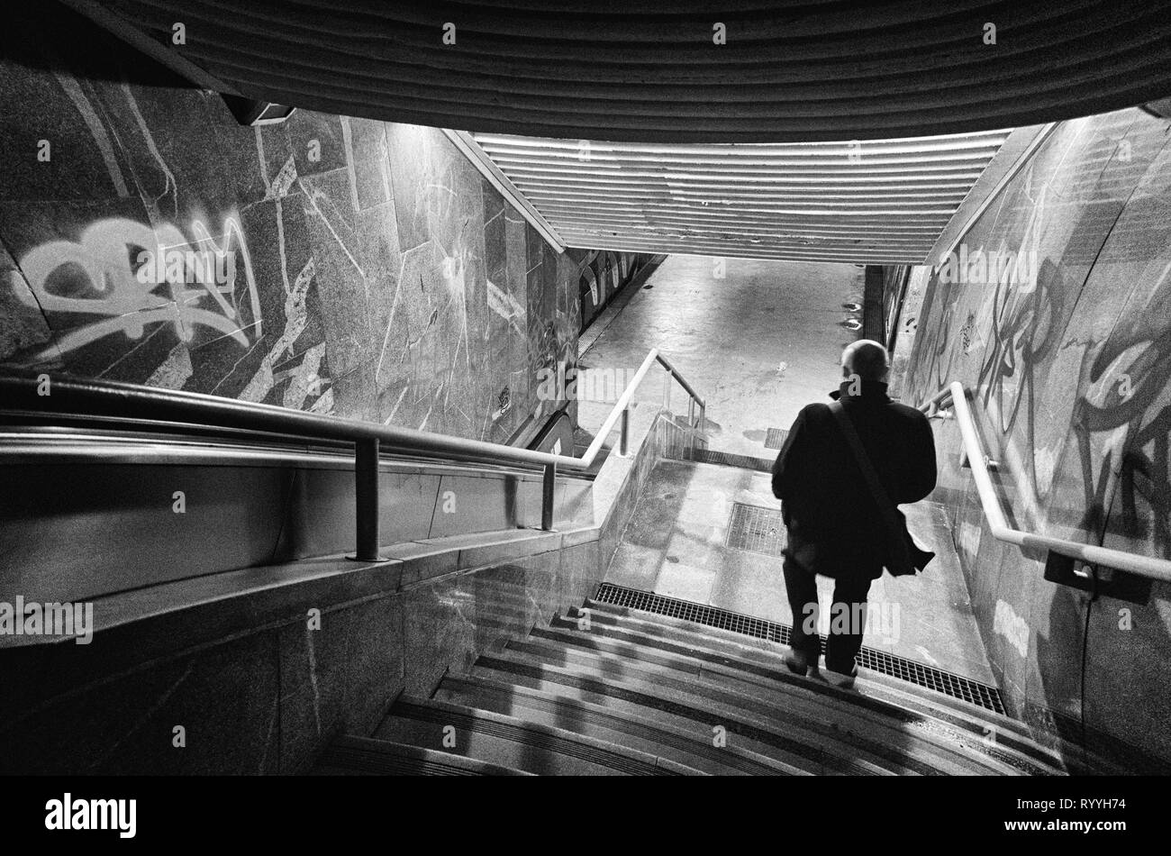 La silhouette di un uomo che sta scendendo le scale nella città metropolitana di notte nella città, la fotografia in bianco e nero Foto Stock