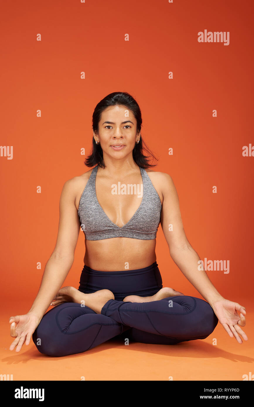 Meditazione yoga posa. Donna sit in Yoga asana su studio orange Colore di sfondo Foto Stock