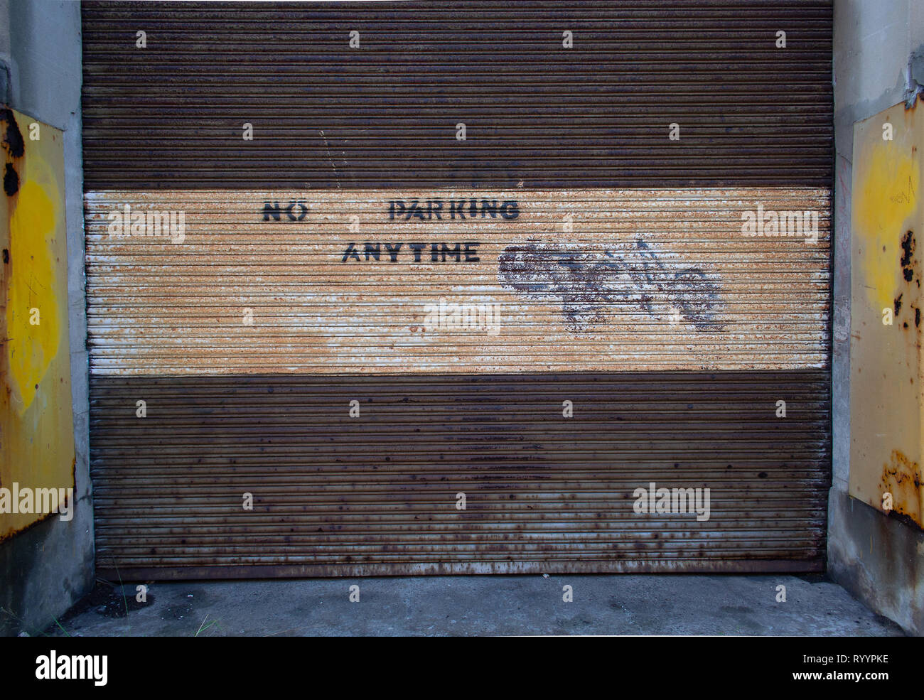 Mano sprrayed parcheggio non segni sul rullo sporco porte in corrispondenza di un magazzino Foto Stock