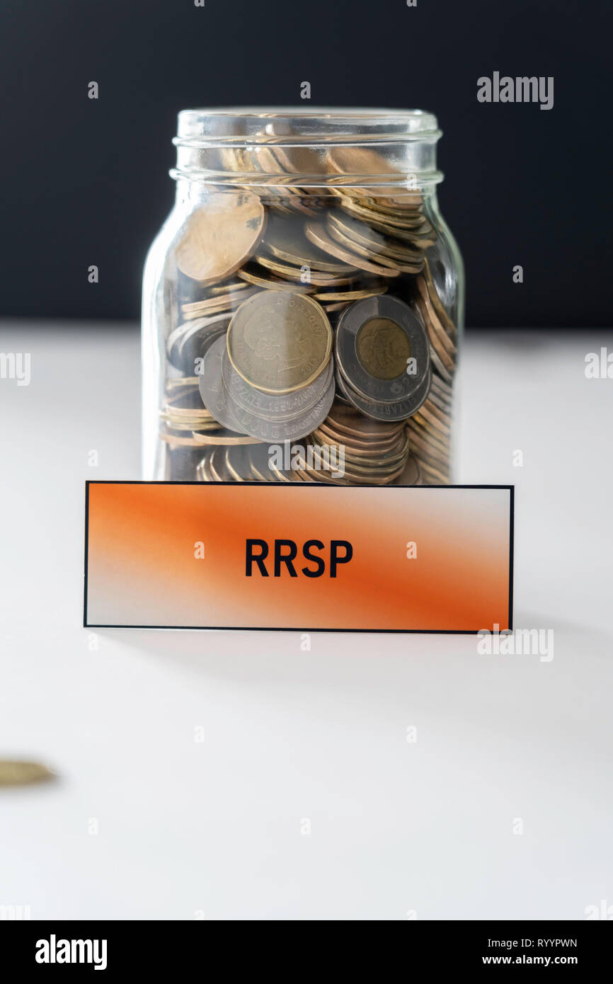 Un vaso pieno di monete per risparmi di RRSP su bianco e sfondo nero Foto Stock