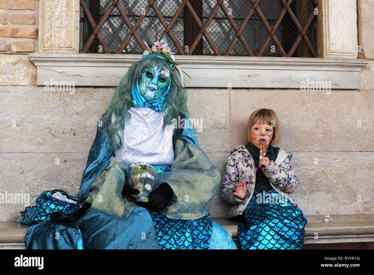 Madre e figlia vestita in un tradizionale maschera e costume per il  Carnevale di Venezia esaurito e sedersi sul banco a Palazzo Ducale, ragazza  a mangiare il gelato Foto stock - Alamy