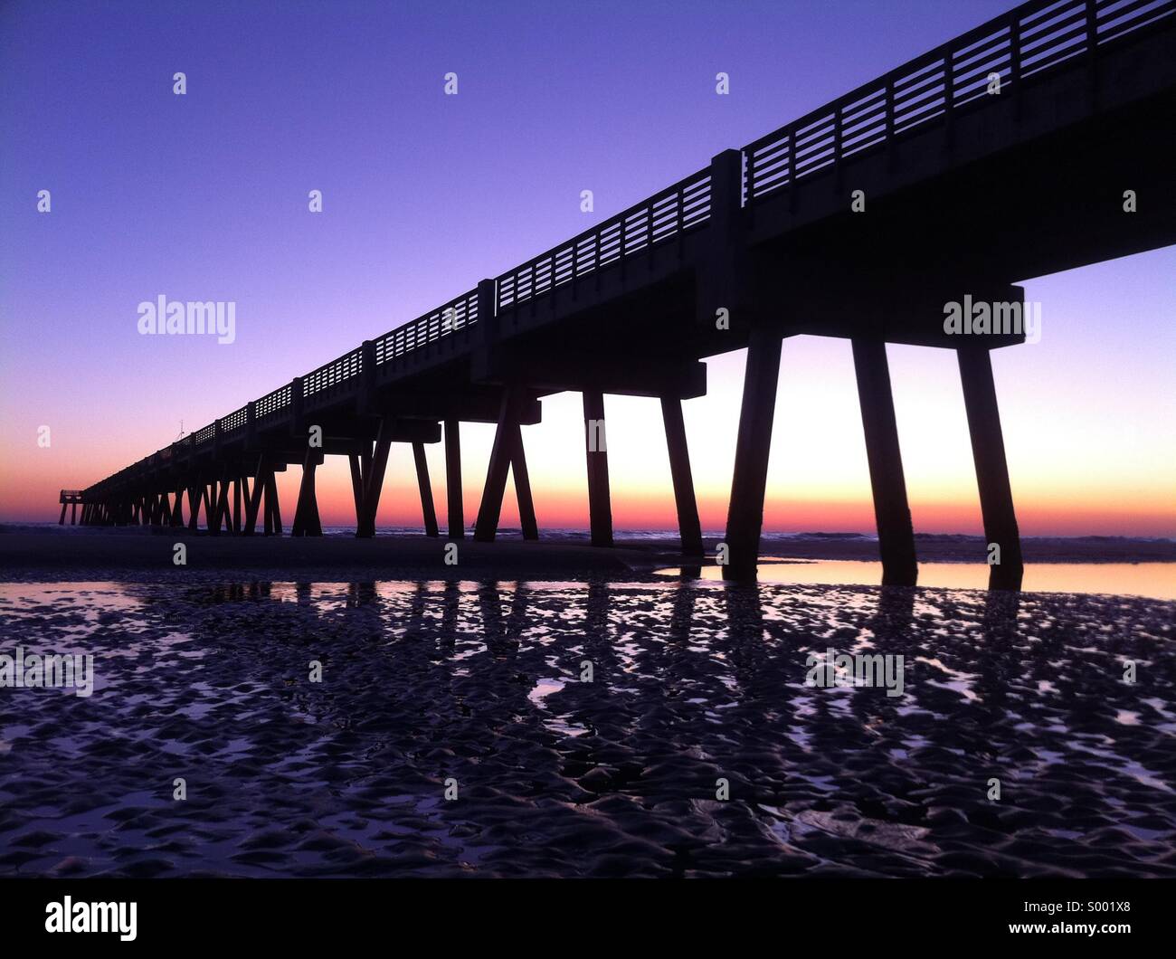 I brillanti colori del tramonto bagnano una mattina presto vista di Jacksonville Beach Pier in North Florida. Stati Uniti d'America. - Immagine stock catturata con smartphone