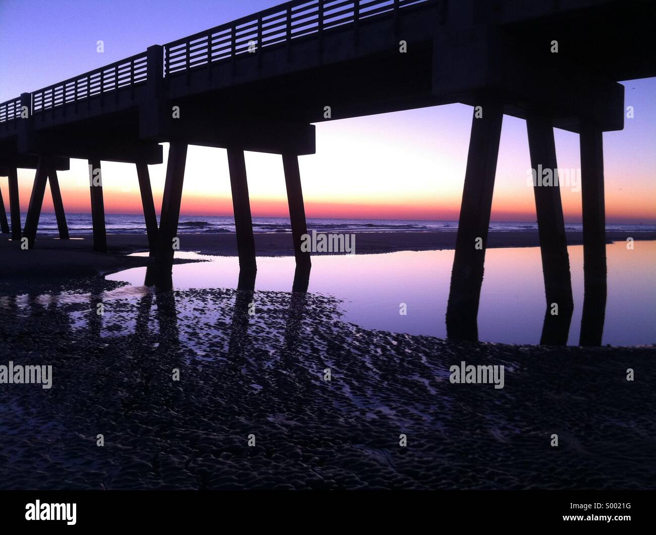 Pool di acqua riflette una vibrante sunrise sky a Jacksonville Beach Pier nella spiaggia di Jacksonville, Florida. Stati Uniti d'America. - Immagine stock catturata con smartphone
