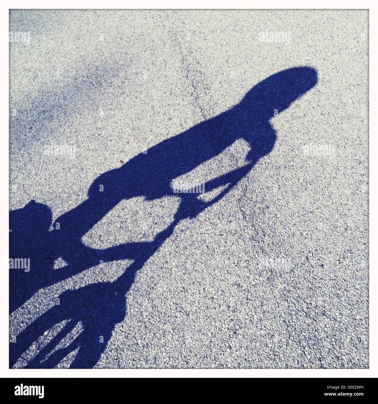 L ombra di una bambina indossa un casco mentre in sella ad una bicicletta. Foto Stock