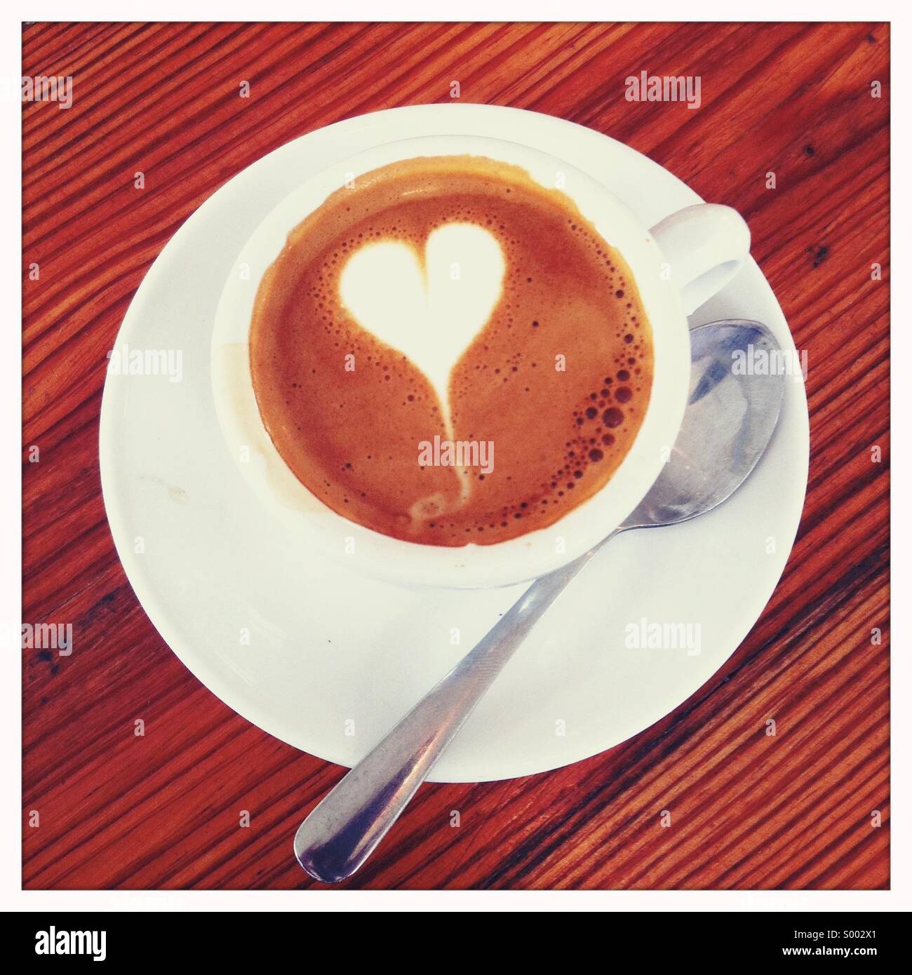 Guardando verso il basso su una bevanda di caffè in tazza con un cucchiaio e una decorata guarnire Foto Stock