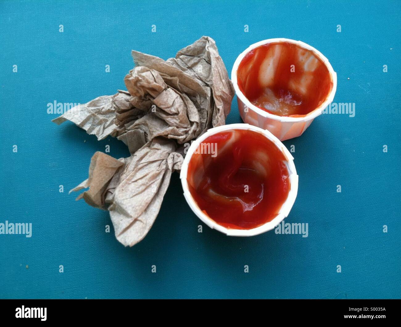 Due utilizzati contenitori di ketchup e un tovagliolo spiegazzato Foto Stock