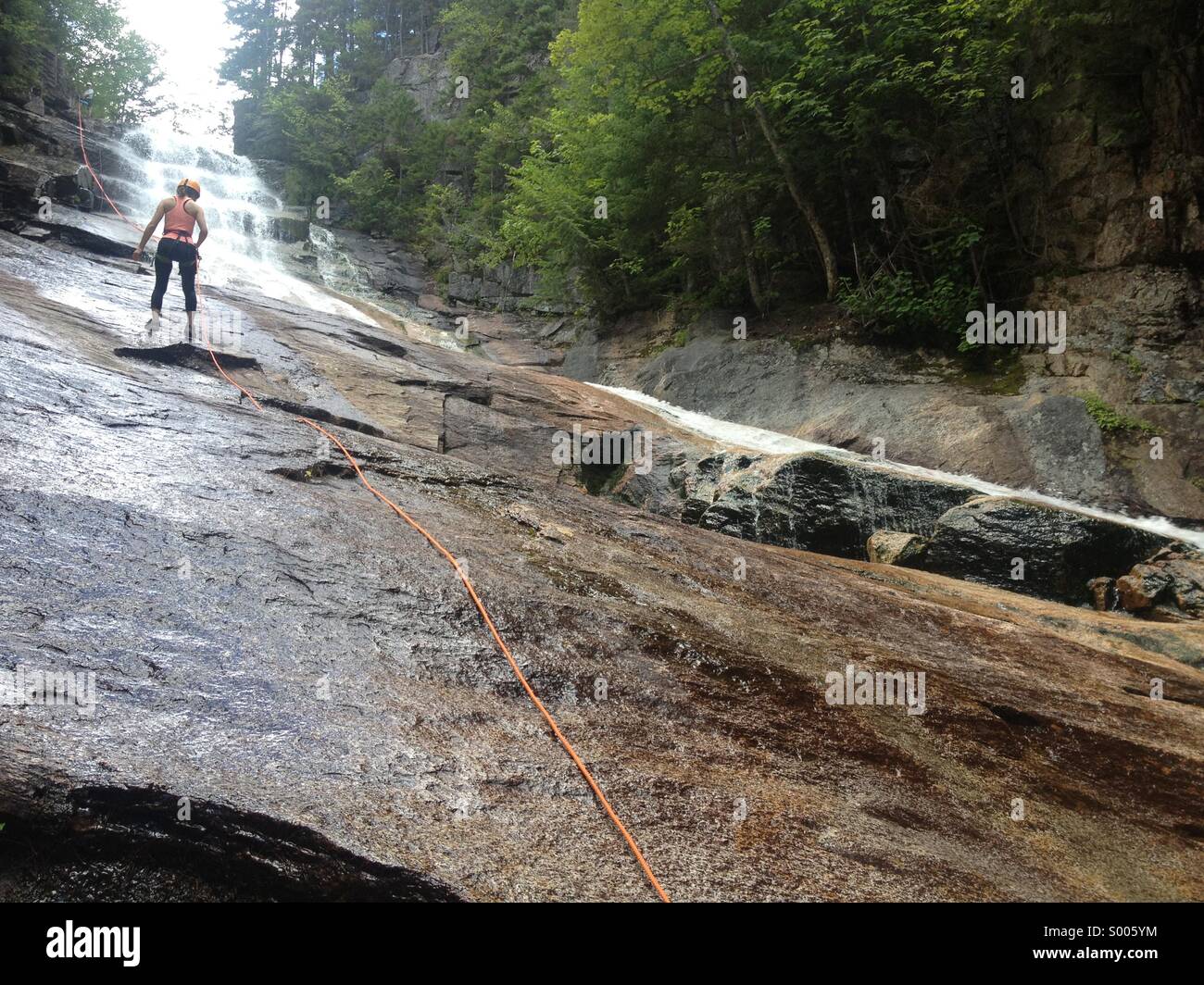 Persona non identificabili rappelling giù una cascata. Ripley cade a Crawford tacca del parco statale, NH, Stati Uniti d'America. Centinaia di persone lo fanno ogni estate e guide di montagna rendono possibile (fotografo il lavoro di giorno) Foto Stock