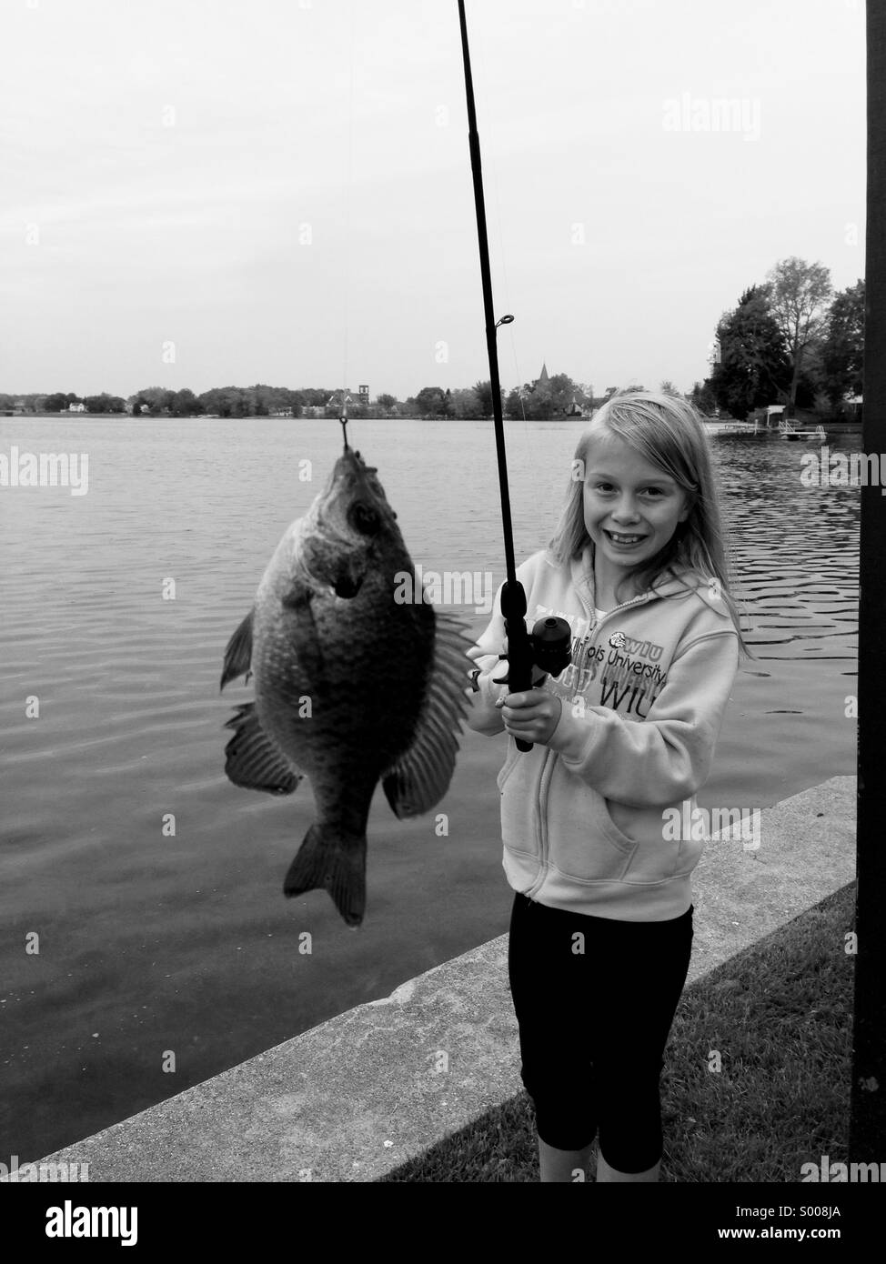 Una giovane ragazza sorride dopo la cattura di un pesce. Foto Stock