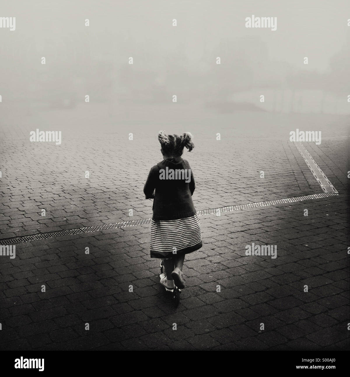 Ragazza giovane con pig-tail scooting nella nebbia led a distanza da una sequenza di salti zig zag linea Foto Stock