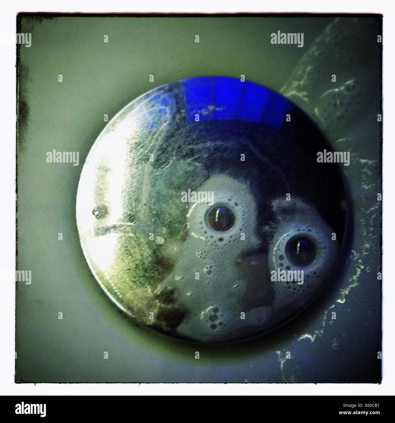 Gli occhi le bolle di sapone in un bacino dissipatore - Immagine stock catturata con smartphone