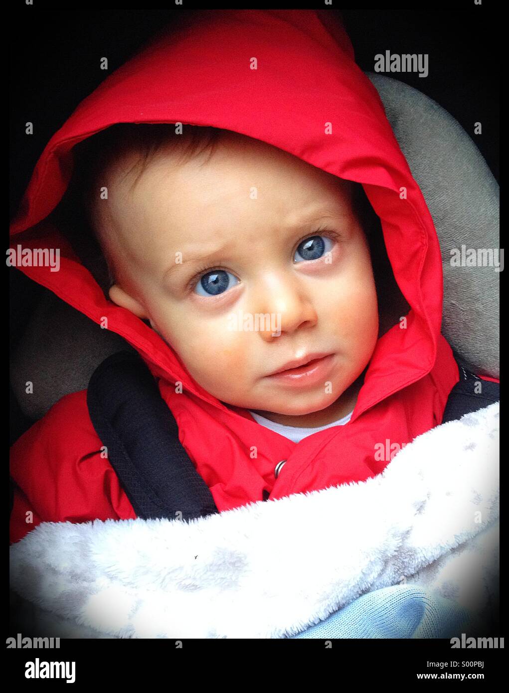 Otto mesi di età bambino seduto nel passeggino con un cappuccio rosso. Foto Stock