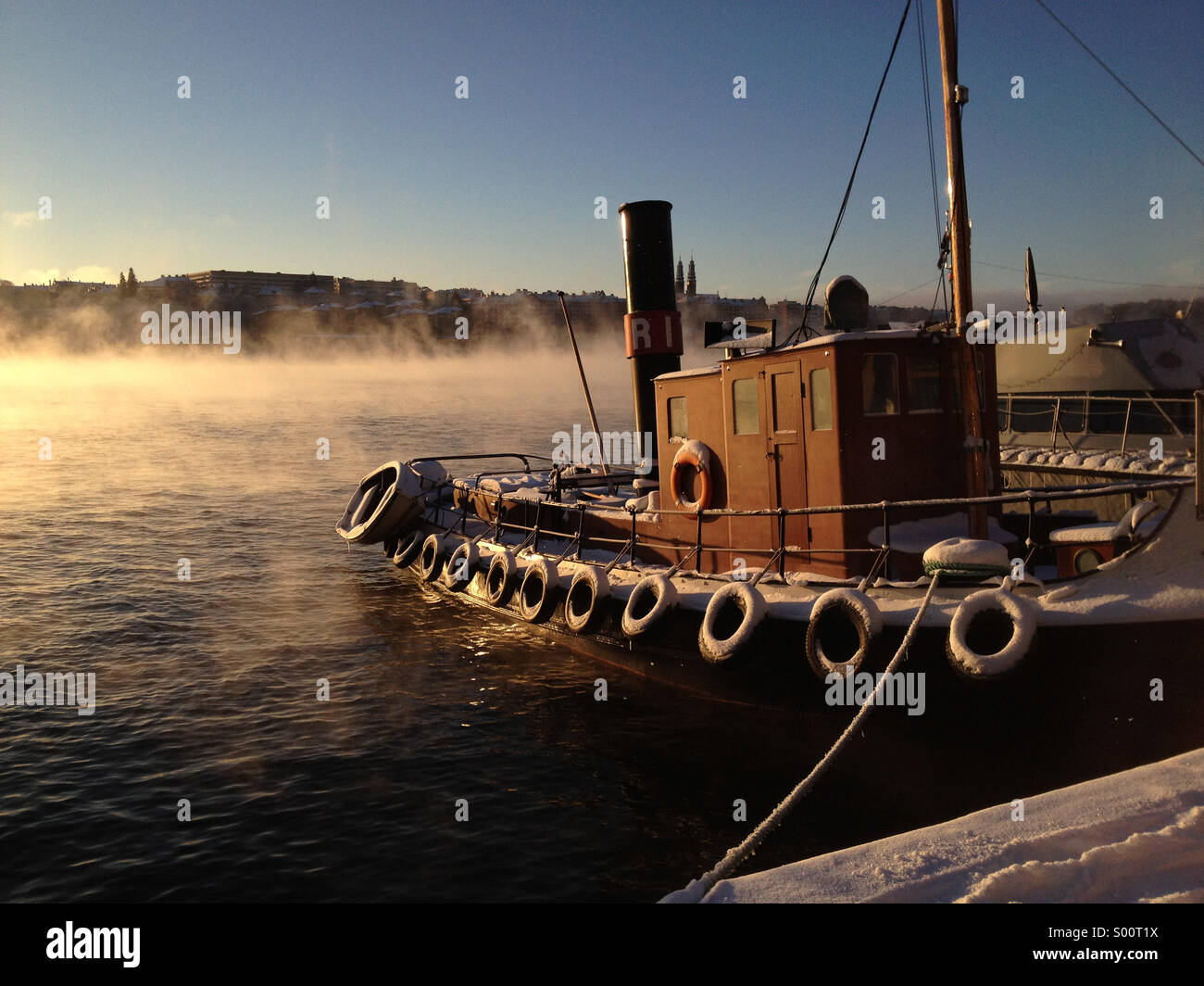 Barca sul lago a Stoccolma centrale come la nebbia sale da inverno acqua all'alba. Foto Stock