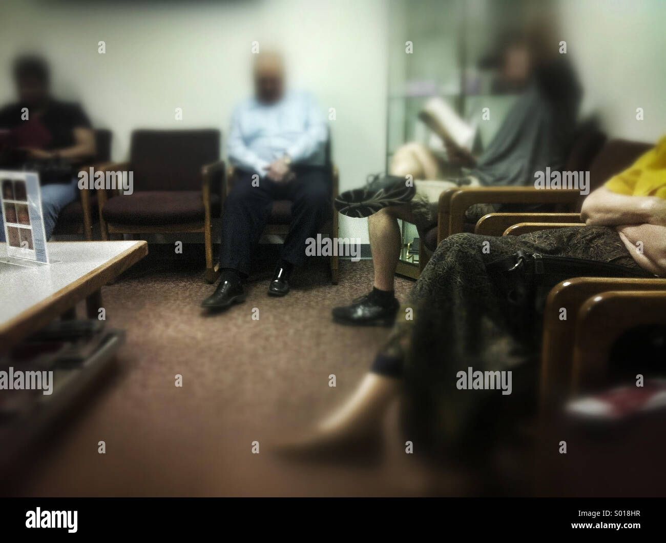 Figure sfocate sedersi in un medico della sala di attesa - Immagine stock catturata con smartphone
