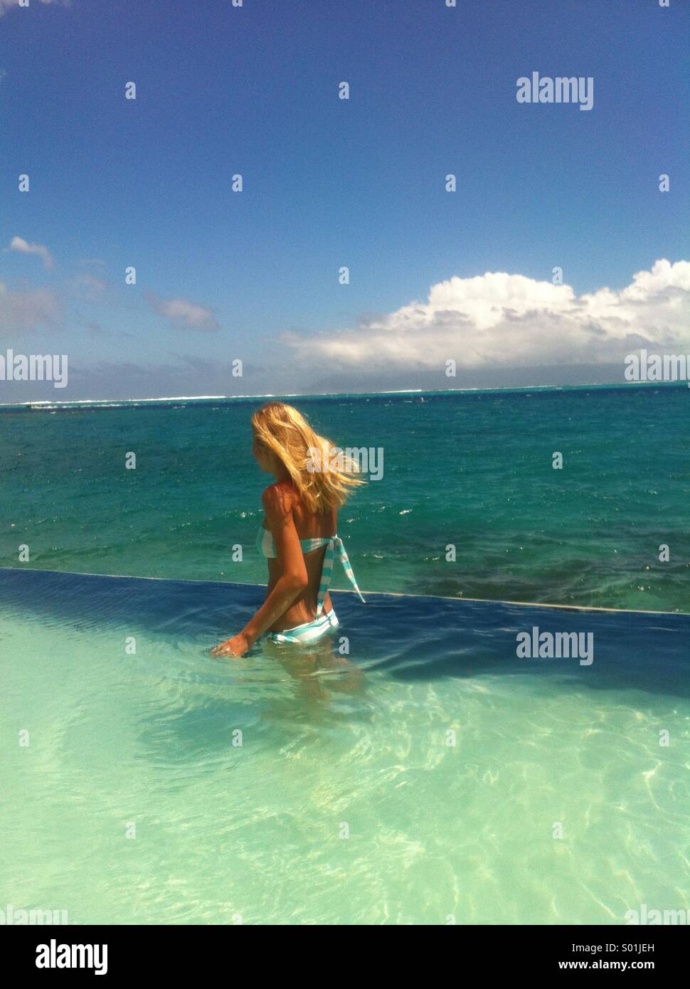 La donna in una piscina infinity dal mare sull'isola di Tahiti in Polinesia francese Foto Stock