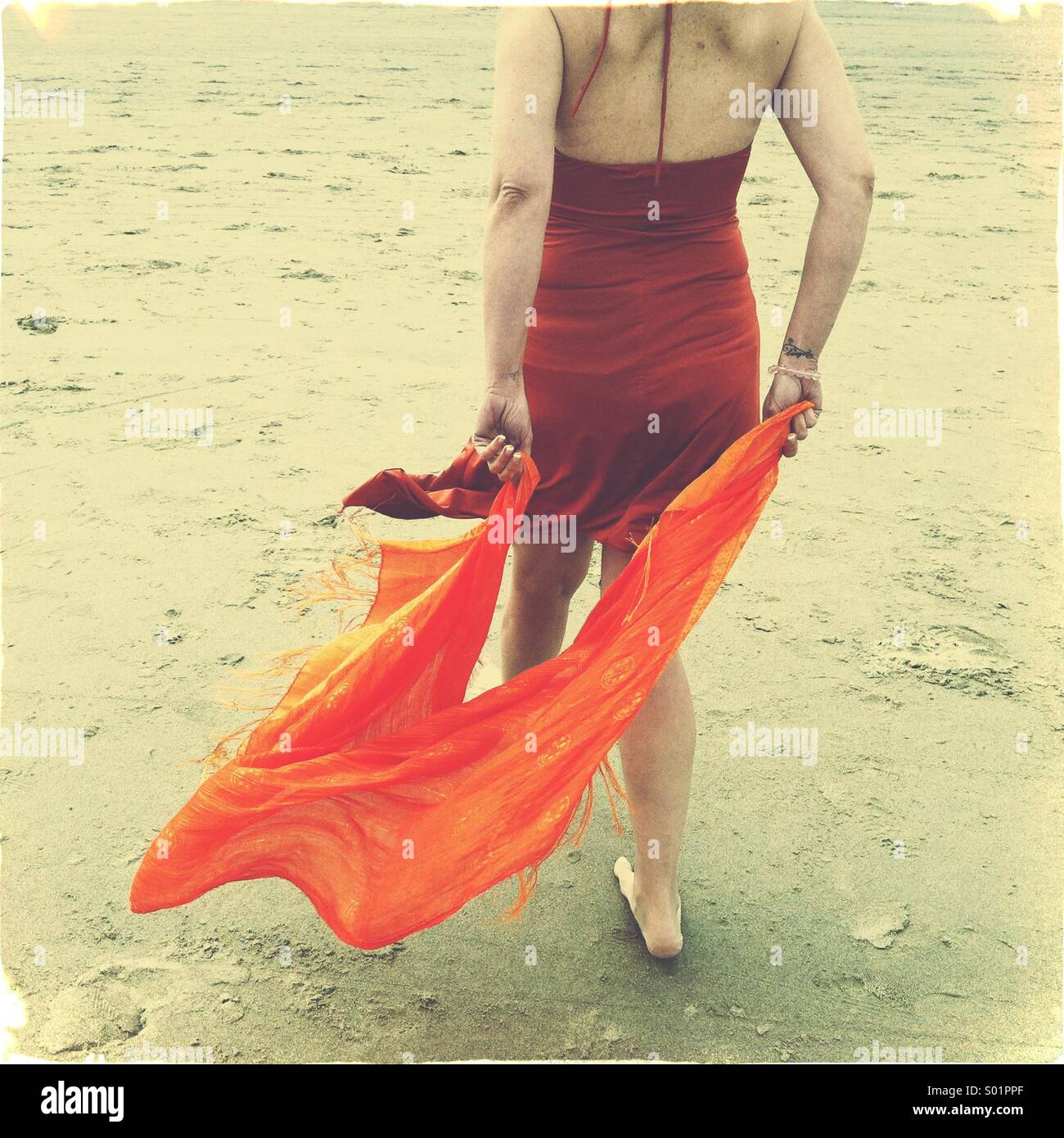 Donna che cammina sulla spiaggia con sciarpa Foto Stock