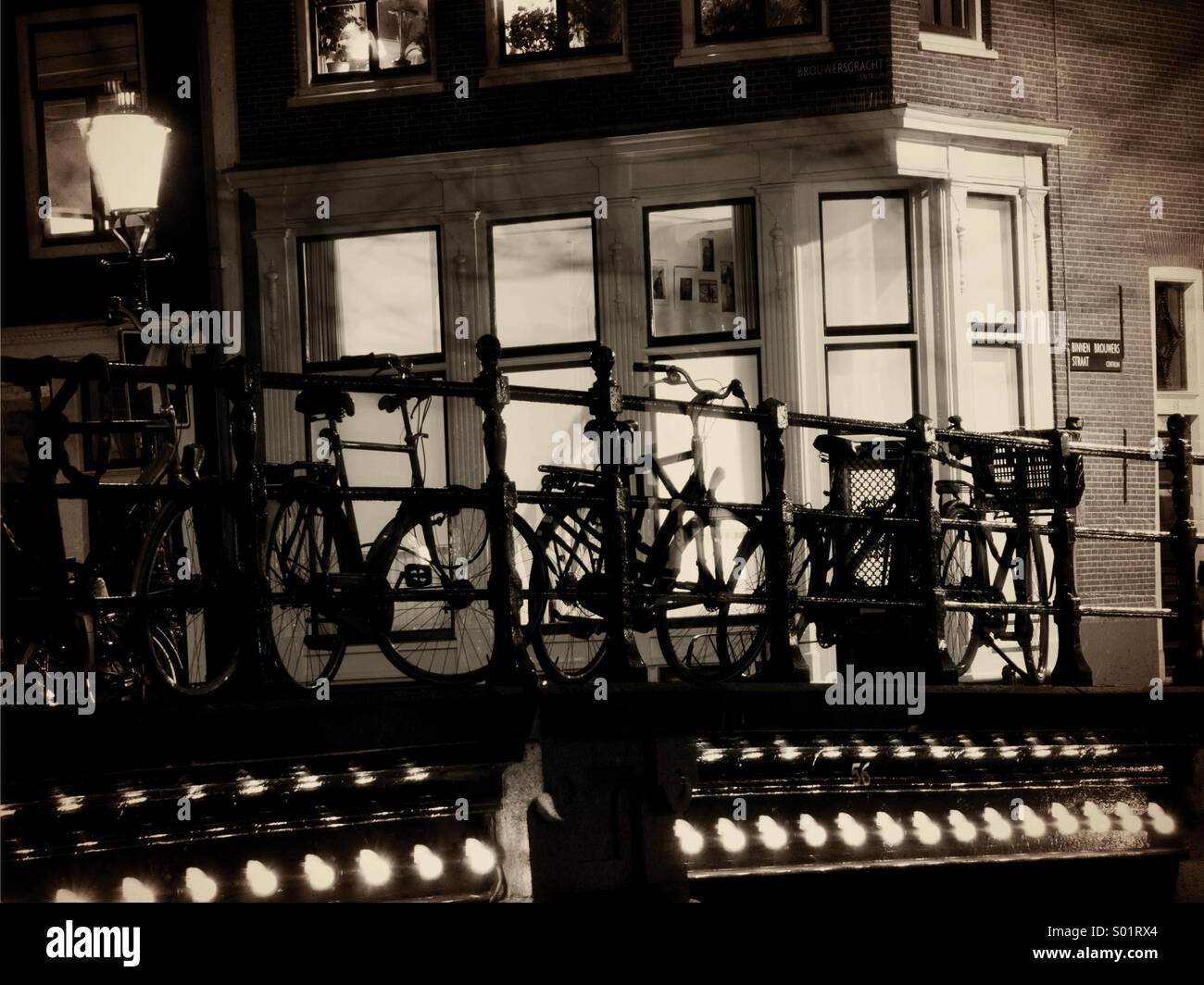 Biciclette bloccato per ringhiere in una notte oscura volta Amsterdam. Foto Stock
