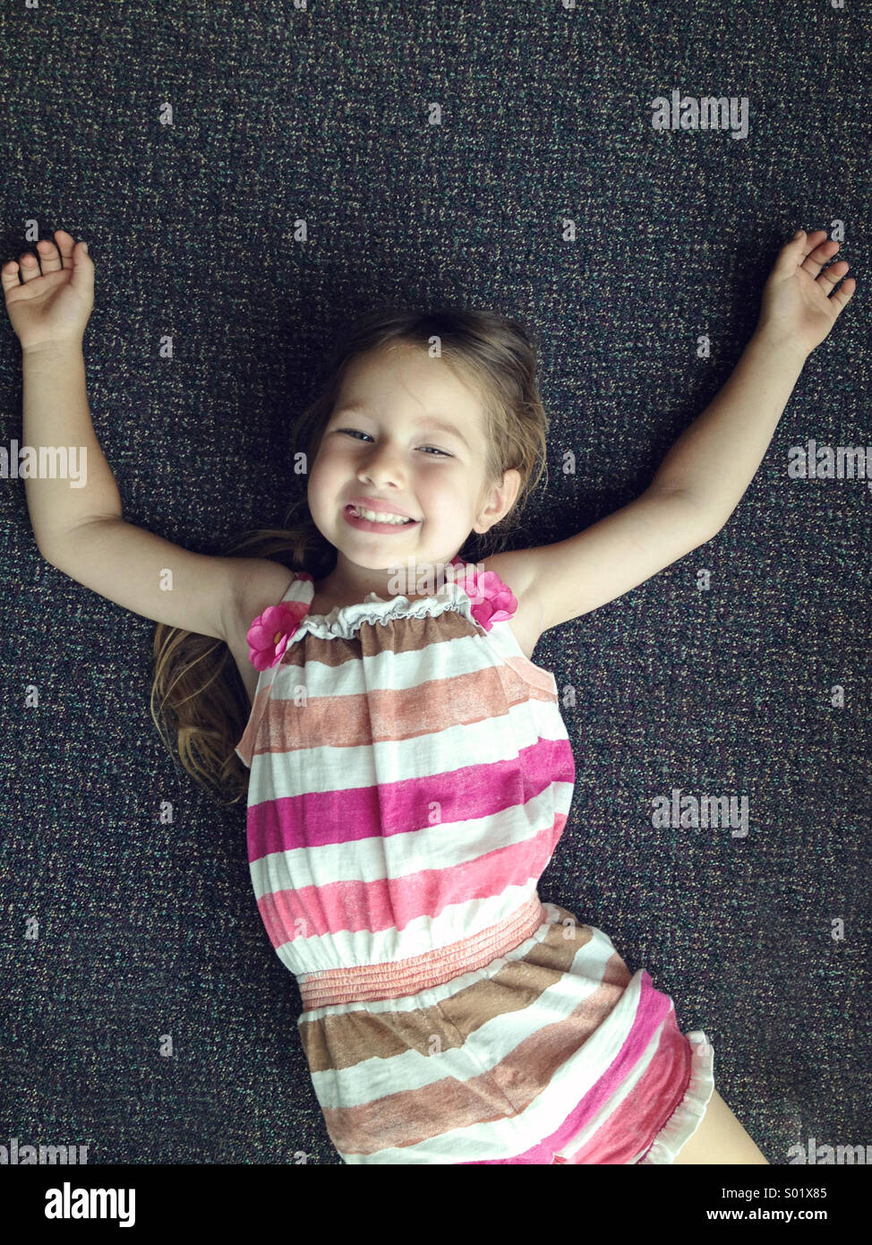 Una giovane ragazza fissa sul pavimento sorridente fino alla telecamera Foto Stock
