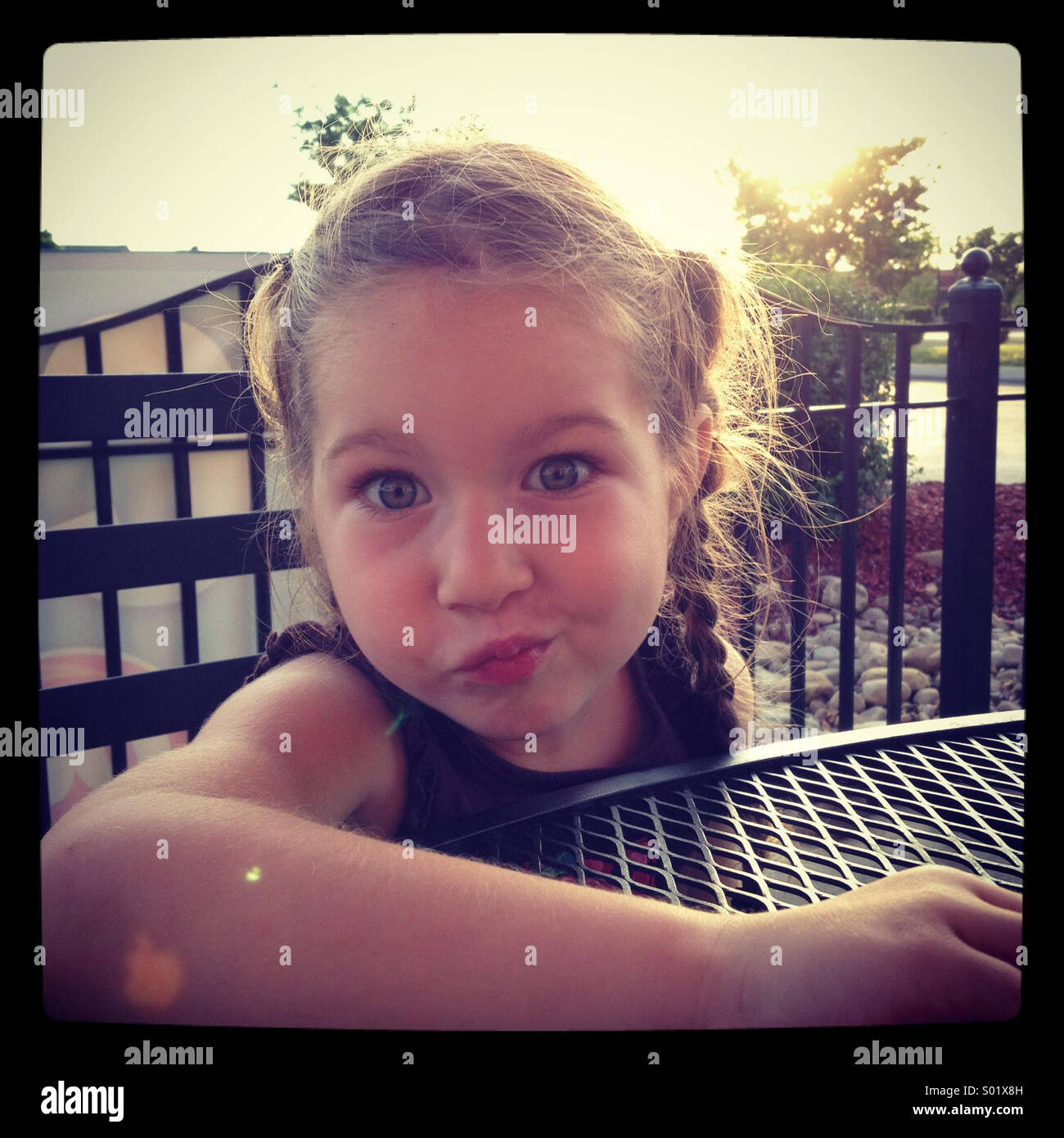 Una bambina fa un divertente volto verso la telecamera Foto Stock