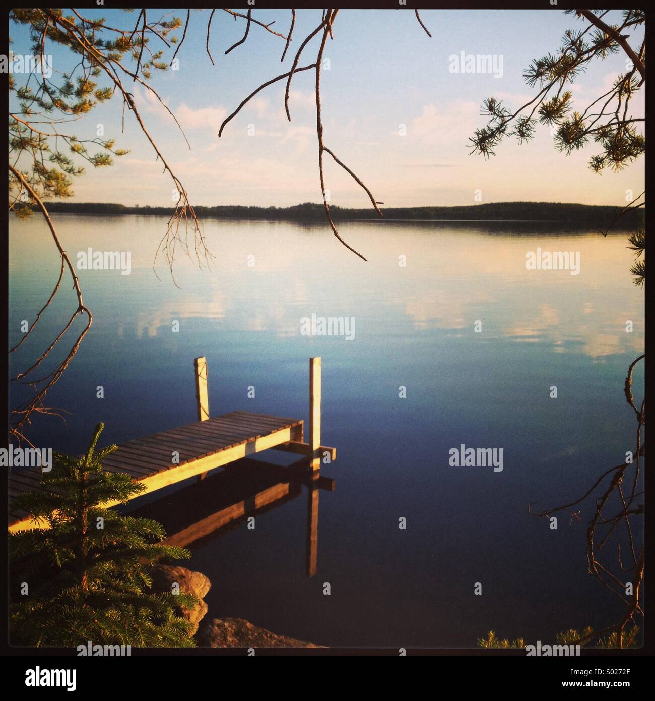 Un calmo lago scandinavo gode del sole di mezzanotte Foto Stock