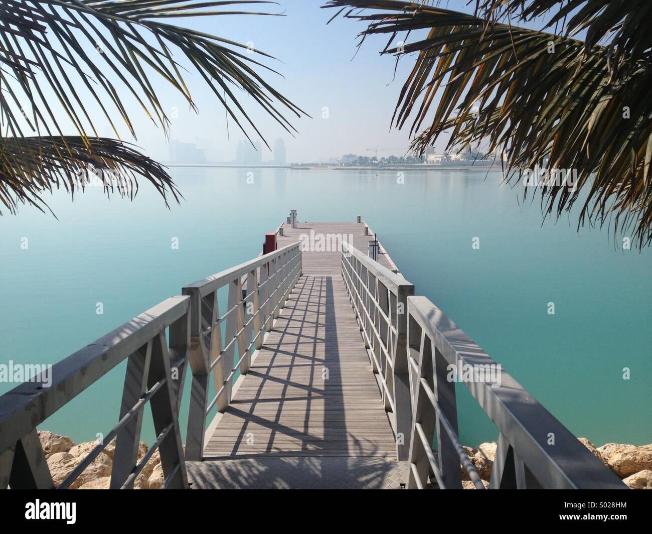 Jetty e palme che si affaccia su Doha skyline della città Foto Stock