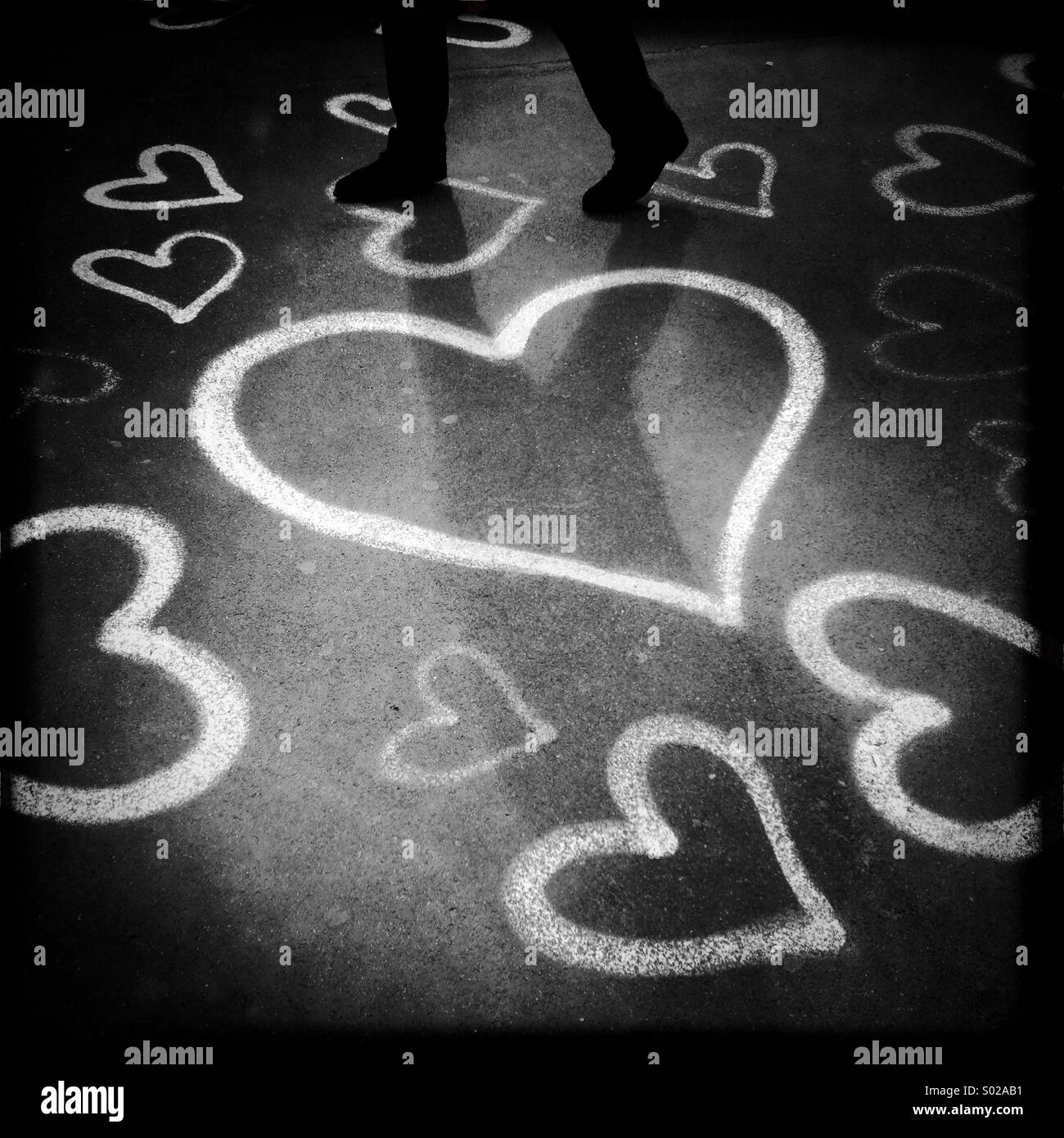 Arte di strada cuore bianco cuori concetto di forma strana amore amante calpestati calpestando sentimenti concetto uomo ombra Foto Stock