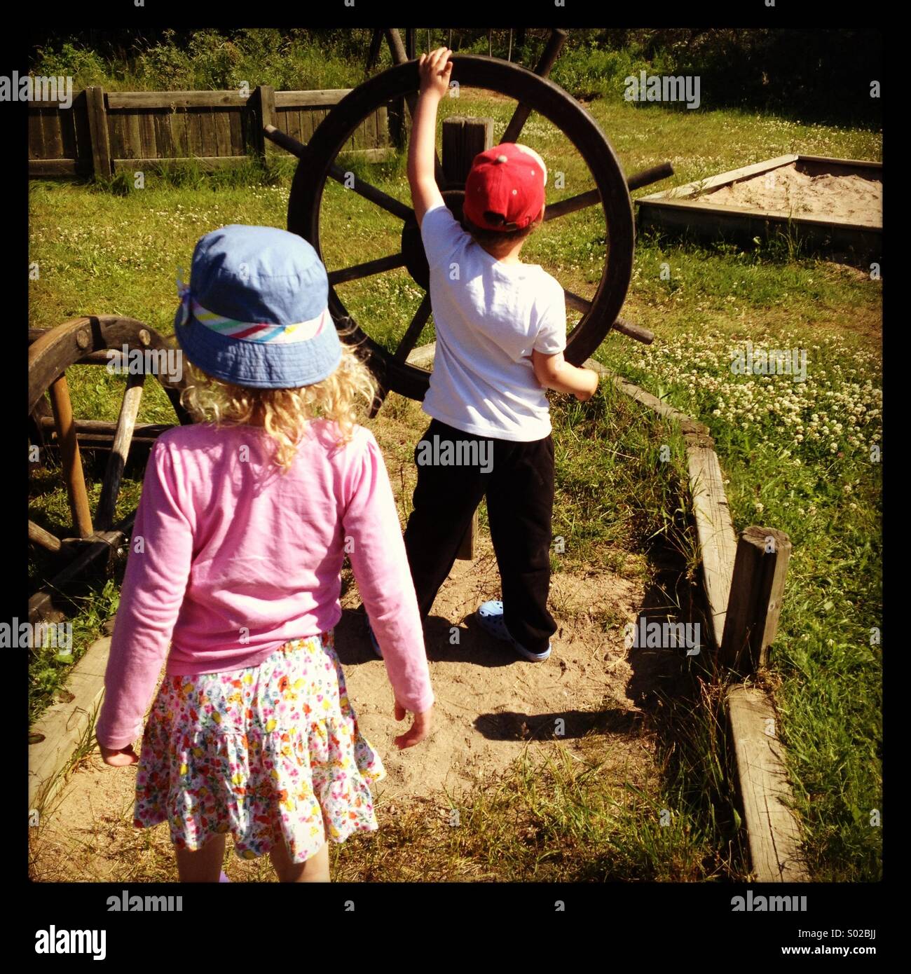 Due bambini fingendo giocando a vela di una nave in un parco giochi pubblico Foto Stock