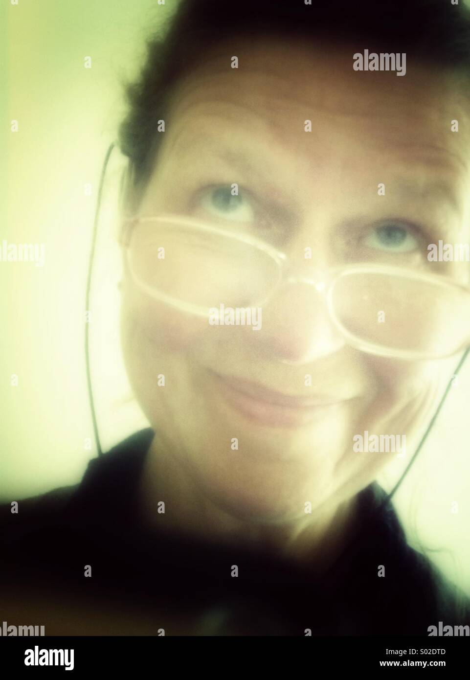 Sorridente donna matura indossa occhiali, guardando verso l'alto Foto Stock