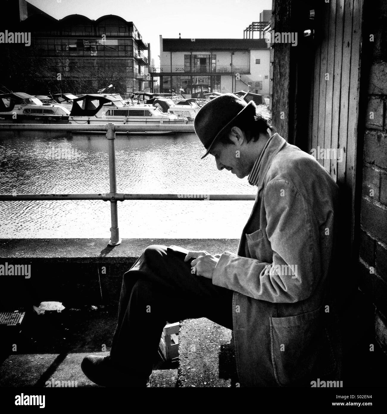 Una candida street shot in Lincoln come un uomo in un cappello si siede da un pool di barche di lettura Foto Stock