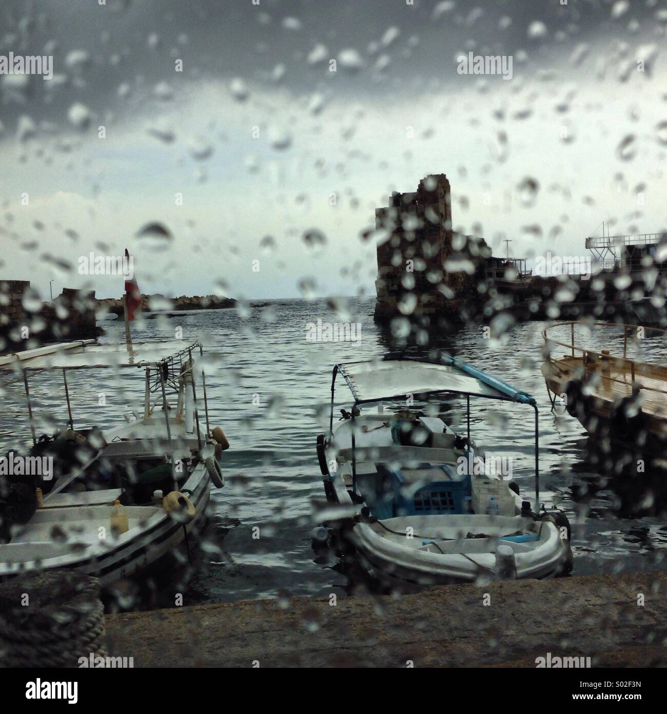 Guardando la pioggia dietro la finestra a Jbeil vecchio porto antico - Libano Medio Oriente - Immagine stock catturata con smartphone