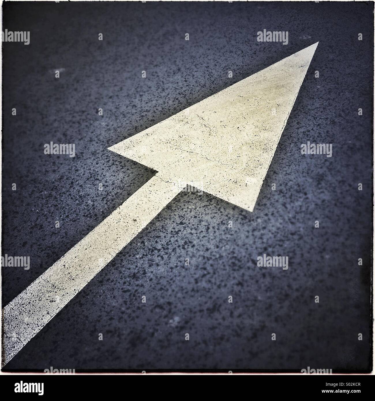 Dipinto di bianco segno di freccia su asfalto Foto Stock