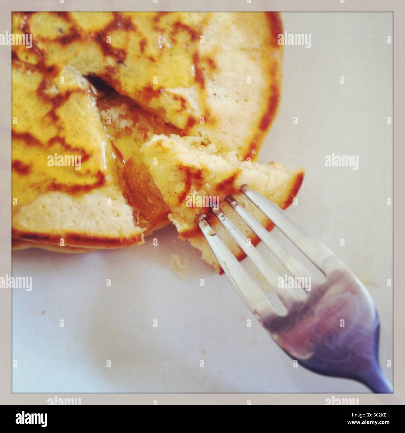 Forcella di prelevare un triangolo di pancake da una pila e rabboccato con sciroppo Foto Stock