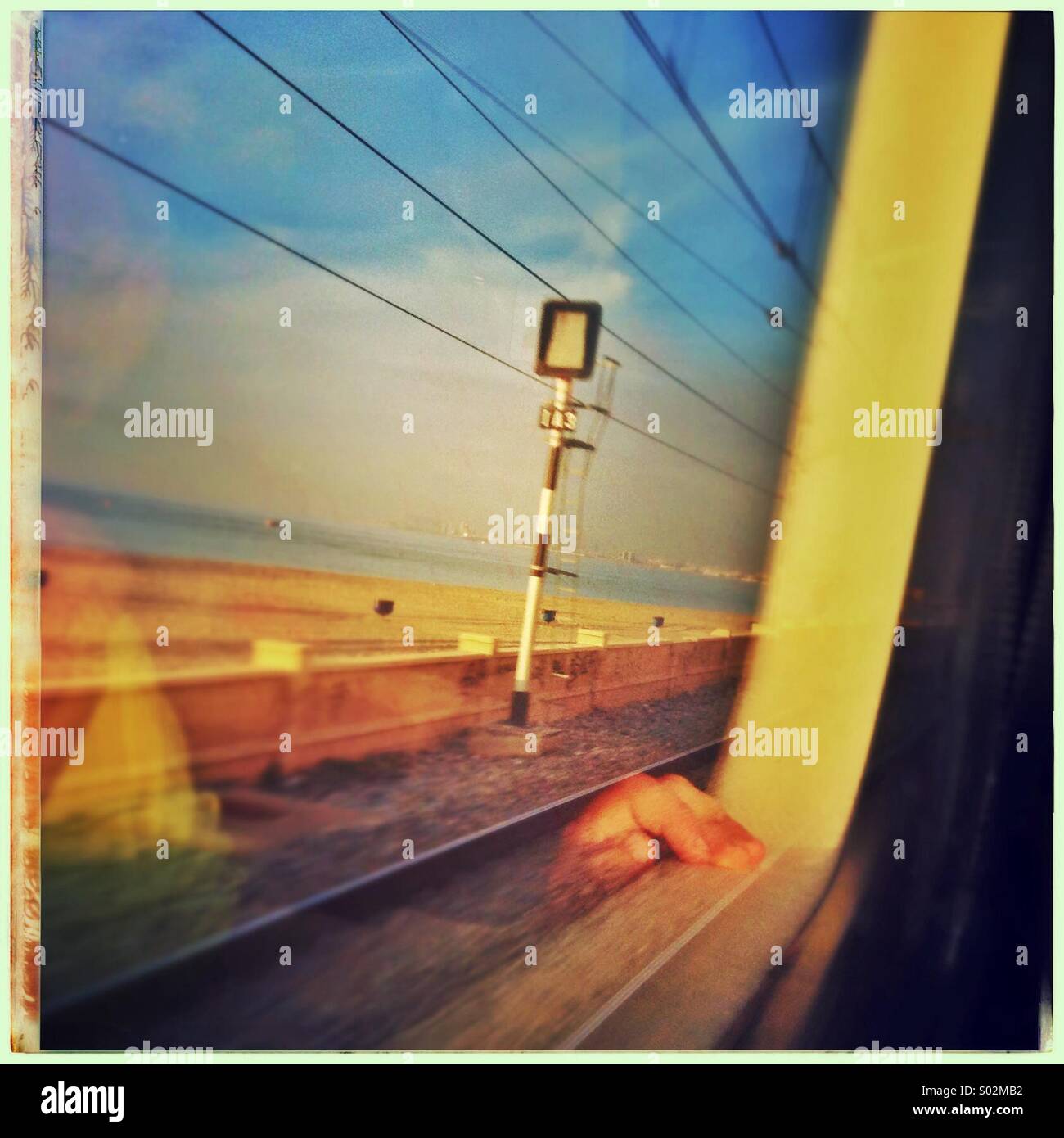 La riflessione di una mano di un giovane ragazzo guardando fuori della finestra del treno a nord della costa di Barcellona, in Catalogna, Spagna Foto Stock