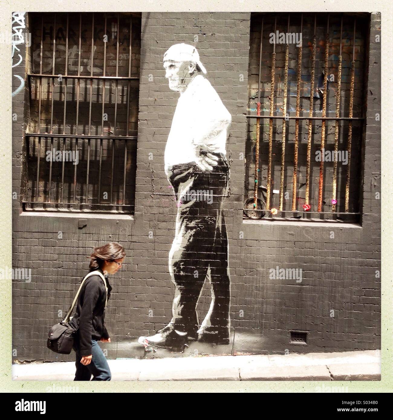 Una donna oltrepassando la street art di un uomo - Immagine stock catturata con smartphone