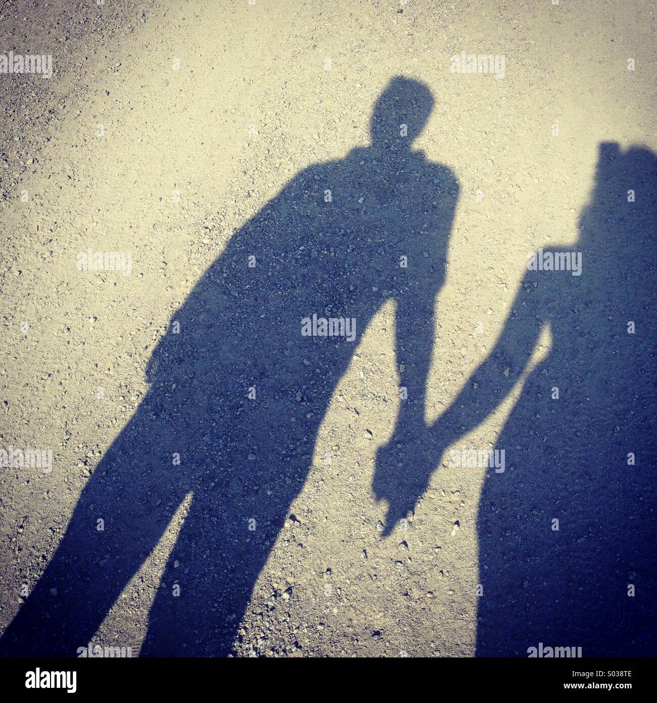 Ombra del giovane tenendo le mani, mentre si cammina in una strada. Foto Stock