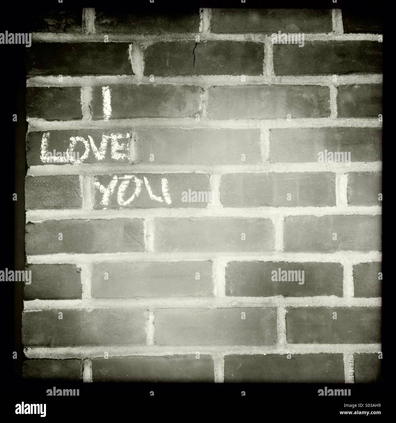 Le parole ti amo scritta in gesso bianco su un muro di mattoni. Foto Stock