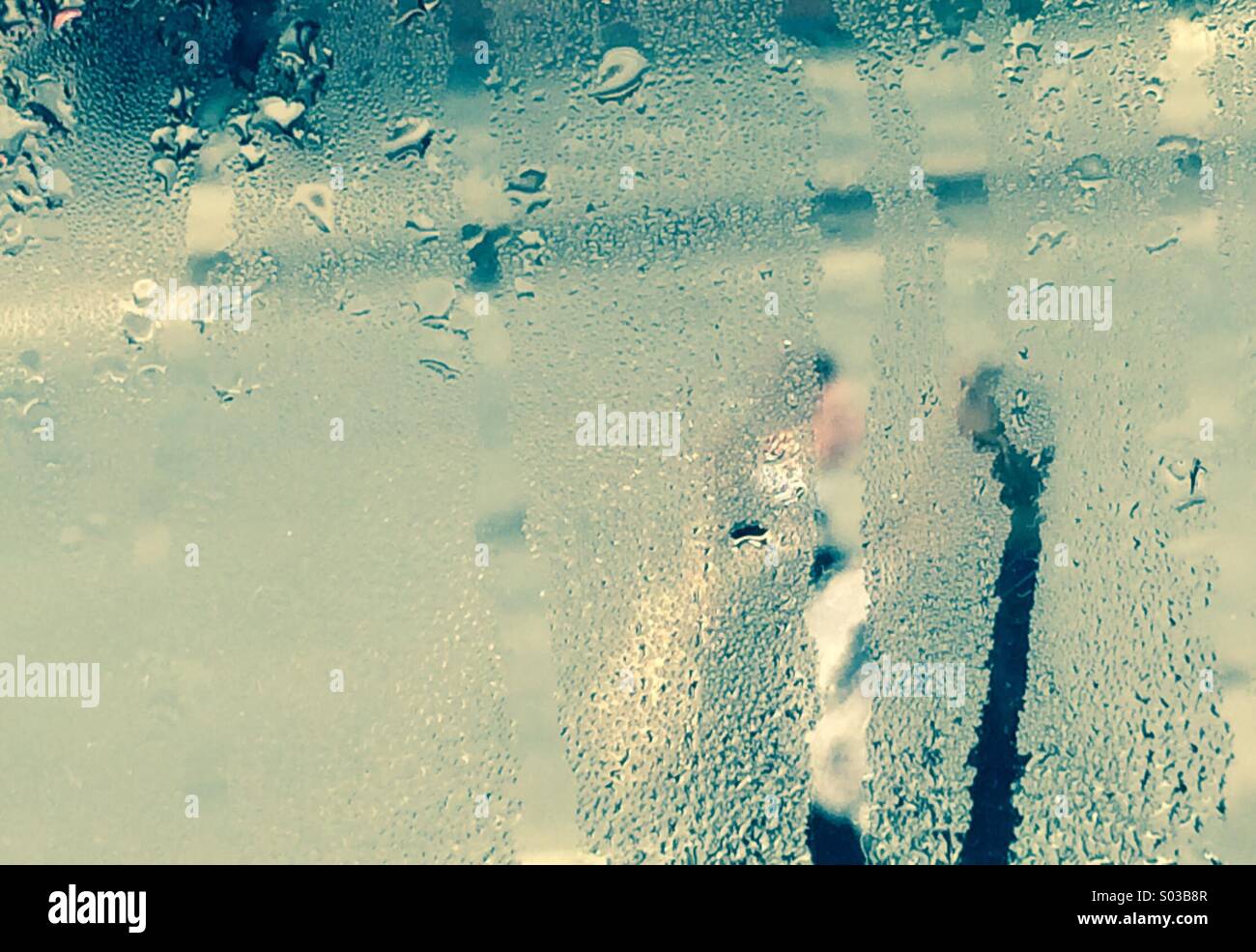 Due persone a piedi lungo la strada visto attraverso la sfocatura di condensa sulla finestra - Immagine stock catturata con smartphone