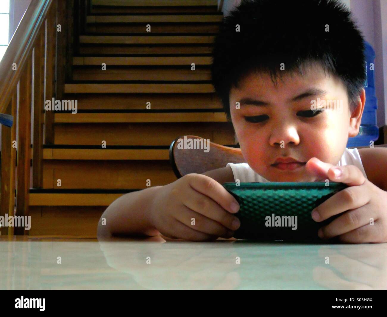 Bambino asiatico boy guardando o la riproduzione su un tablet phone Foto Stock