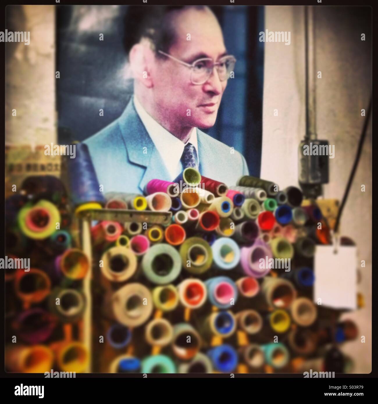 Ritratto di uomo sulla parete dietro rocchetti di filato all'interno di sartoria - Immagine stock catturata con smartphone