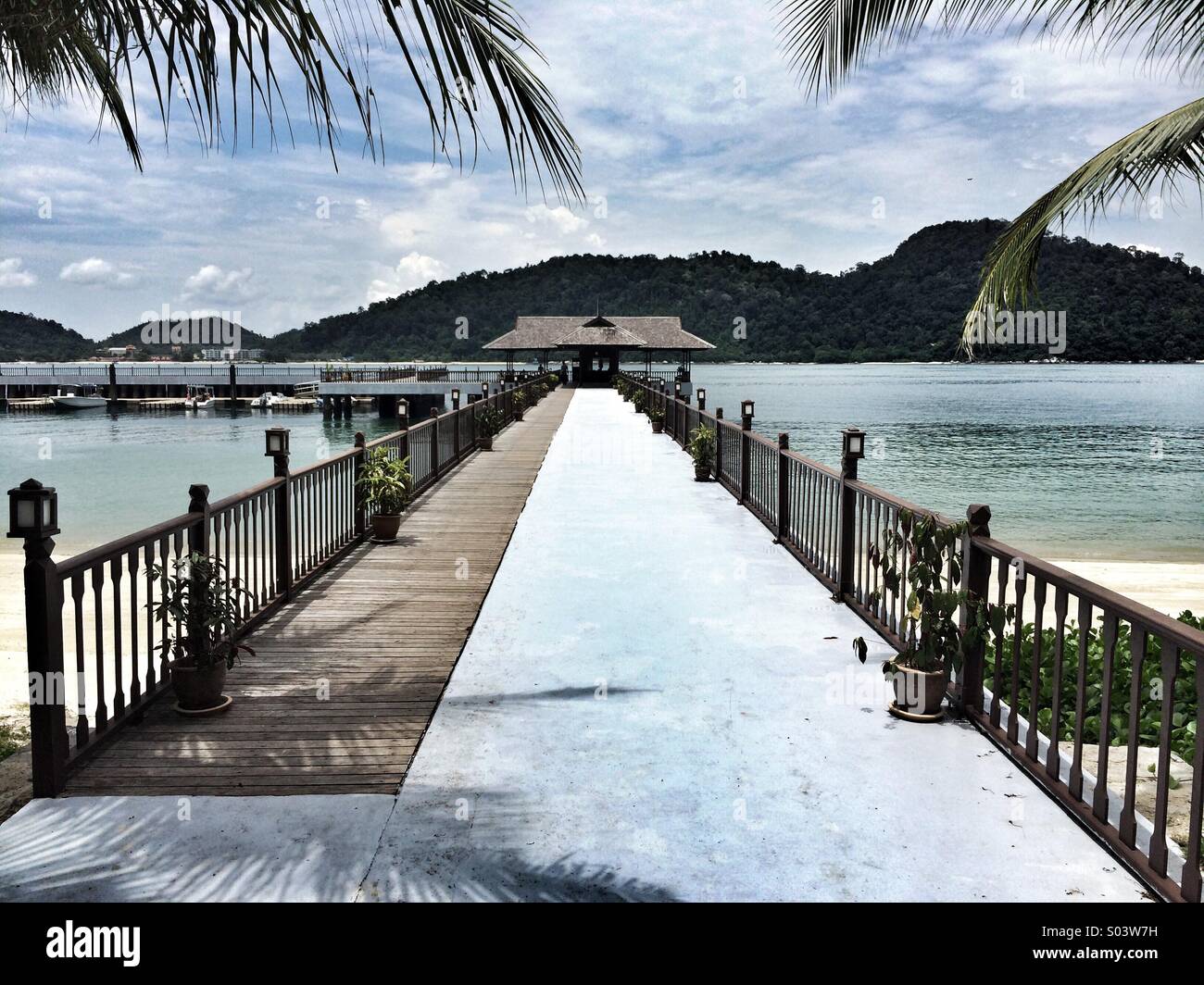 Molo di cemento la passerella con un sfondo collinare in un'isola tropicale Foto Stock