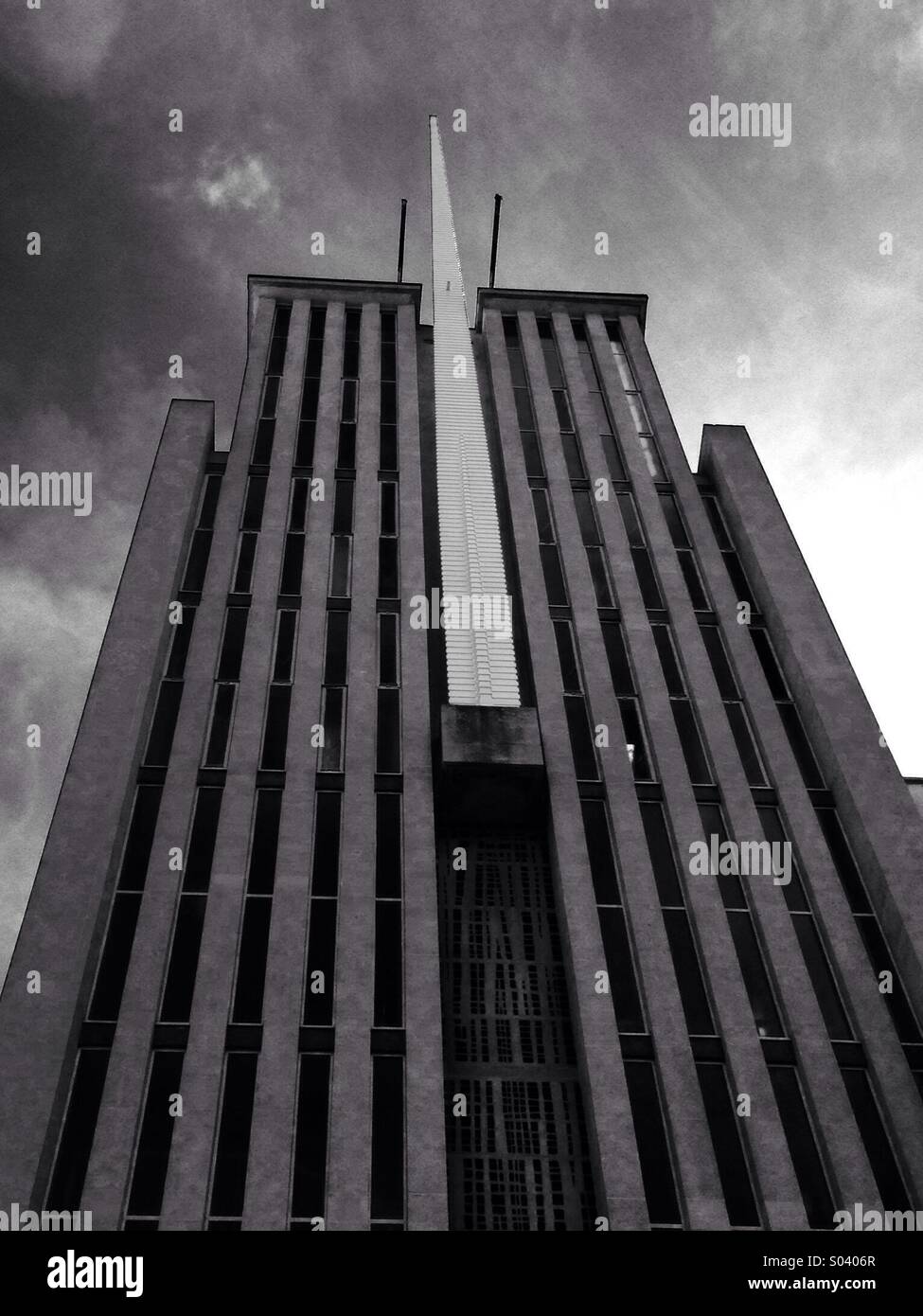 Campanile di una chiesa moderna architettura guardando come Gotham City contro minacciose nuvole in bianco e nero Foto Stock