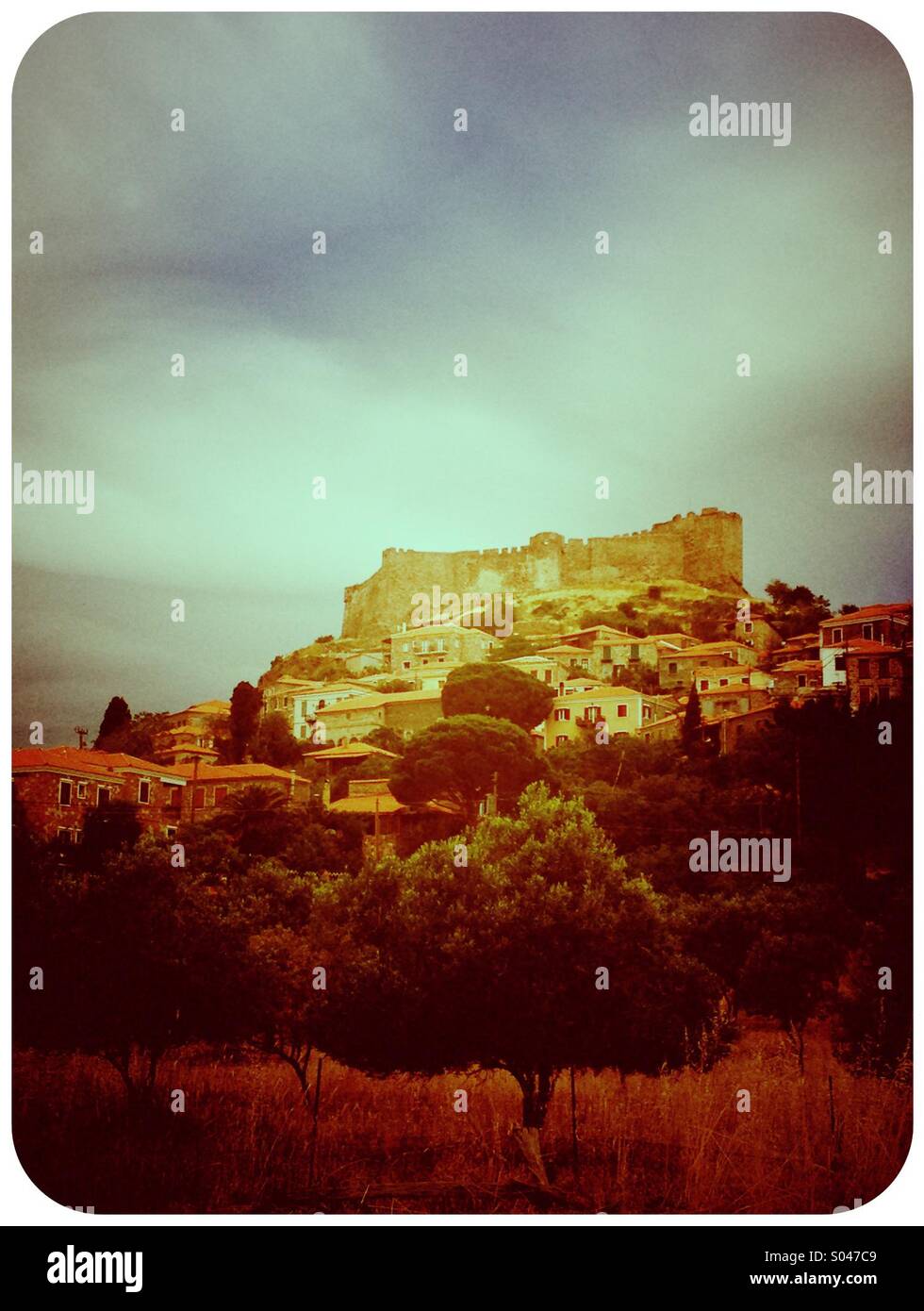 Castello che domina un villaggio greco prima della tempesta Foto Stock