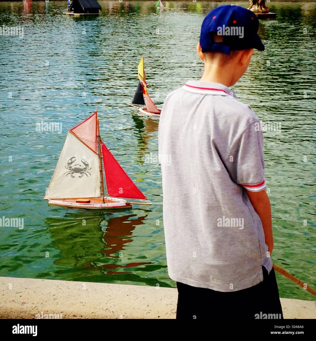 Giovane ragazzo giocattolo di vela Barche a vela nei Giardini del Lussemburgo a Parigi Foto Stock