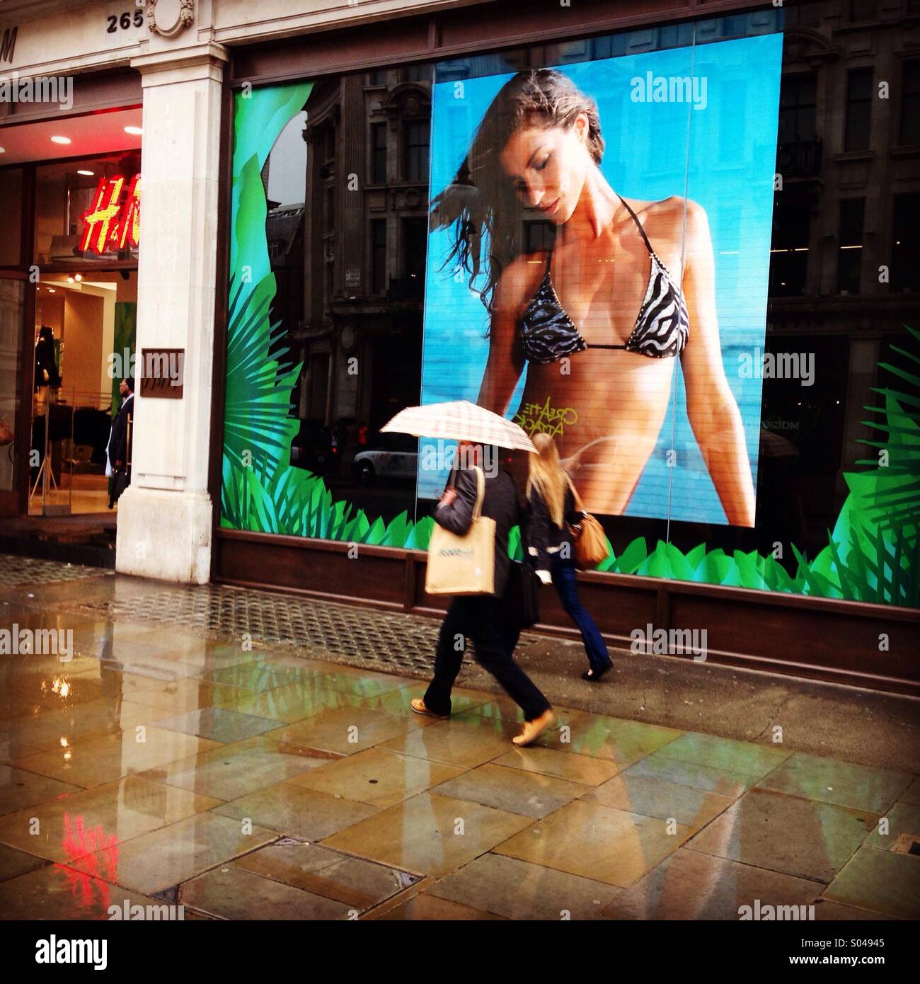 Estate spiaggia-ware mode pubblicizzato su una fredda e piovosa Oxford Street, Londra. Foto Stock