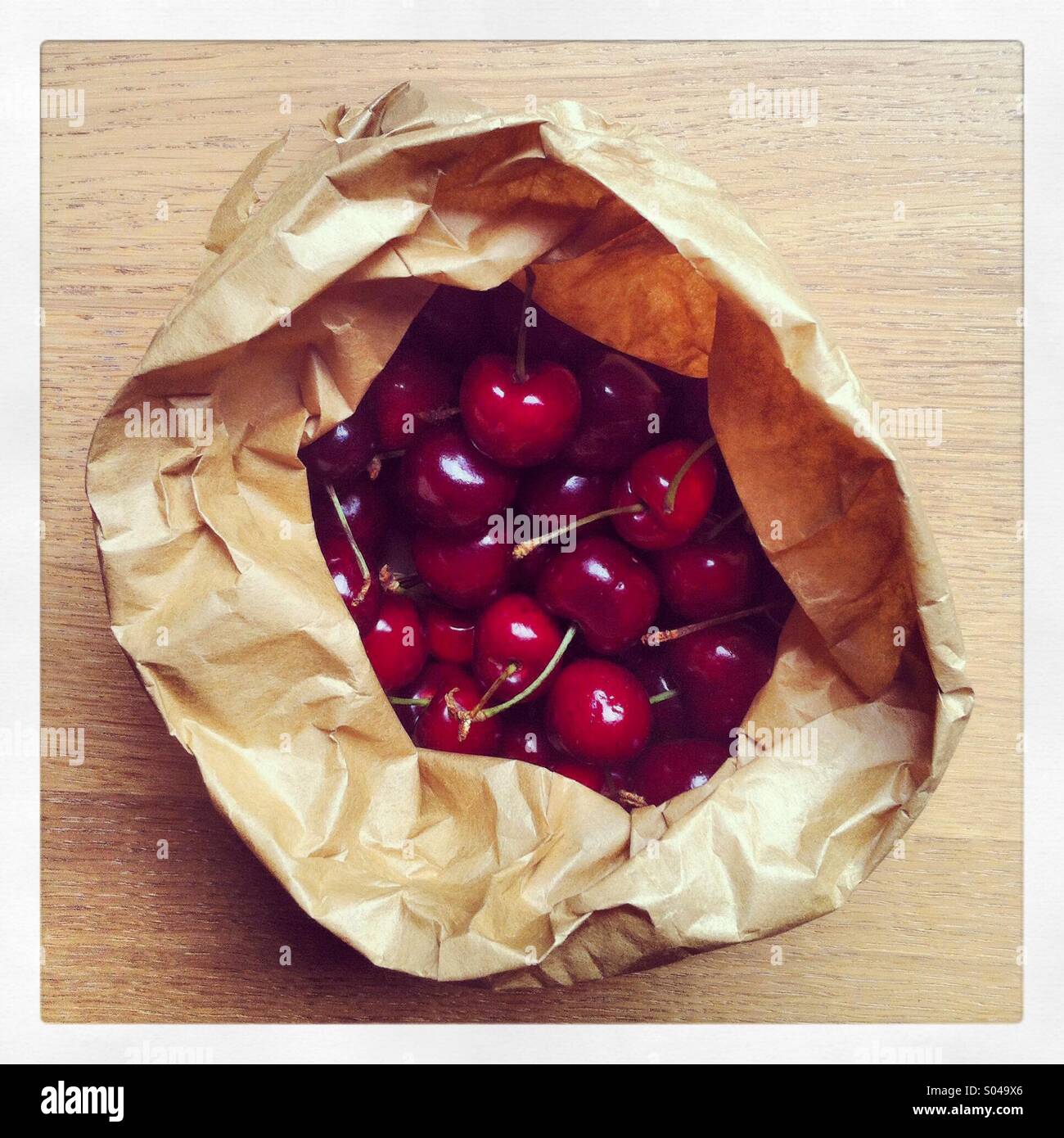 Un sacco di carta pieno di ripe ciliege rosse fresche dal mercato Foto Stock