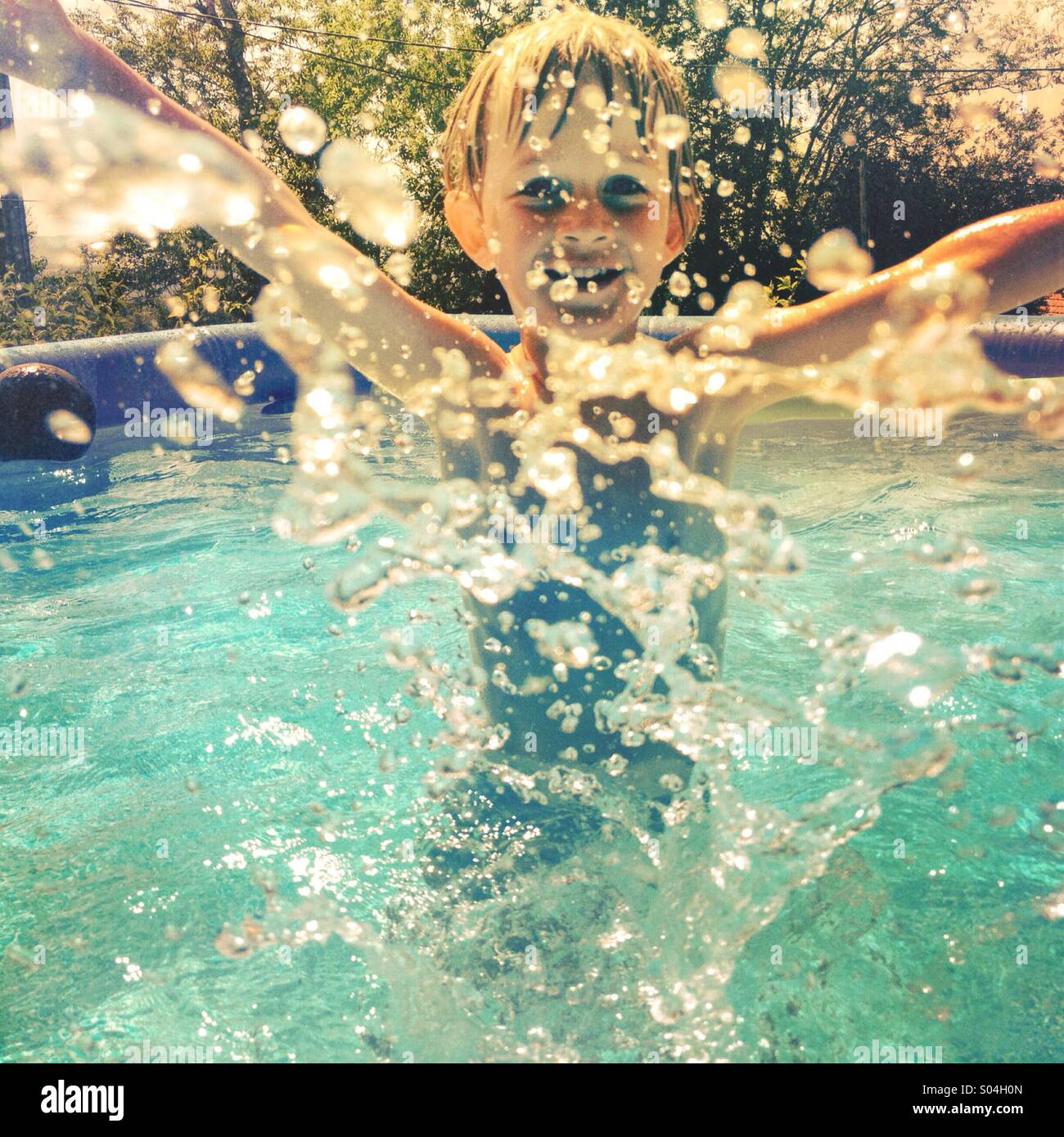 Ragazzo giovane spruzzi in piscina Foto Stock