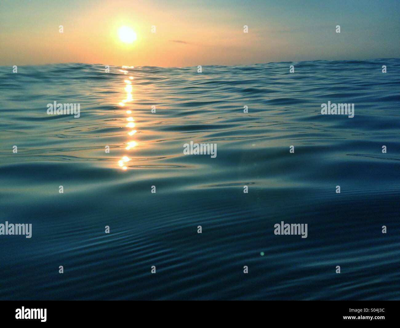 Tramonto dal mare con la luce del sole che riflette sulla superficie Foto Stock