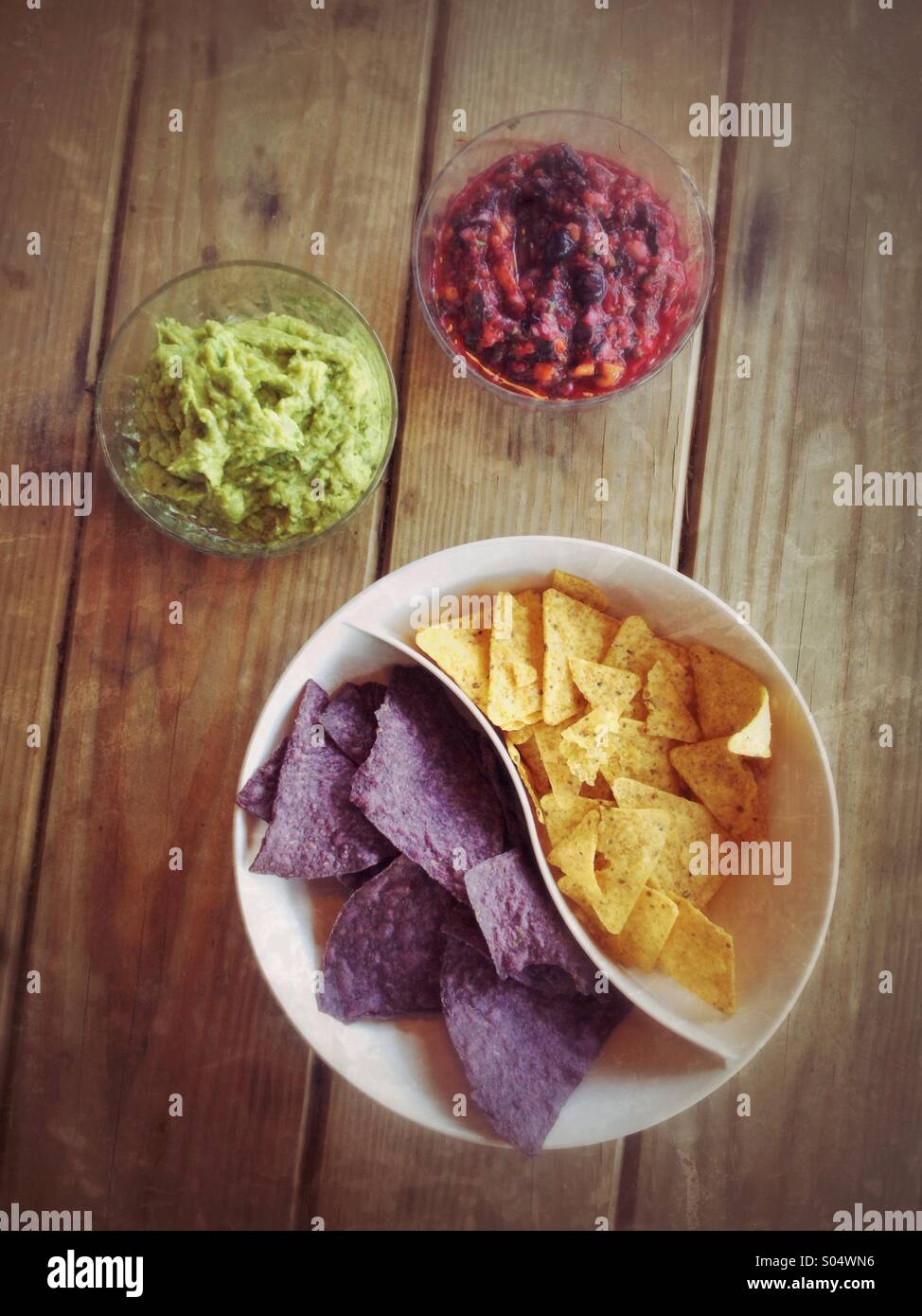Bocce di mirtillo salsa guacamole, giallo e blu di corn chips sul tavolo da picnic Foto Stock